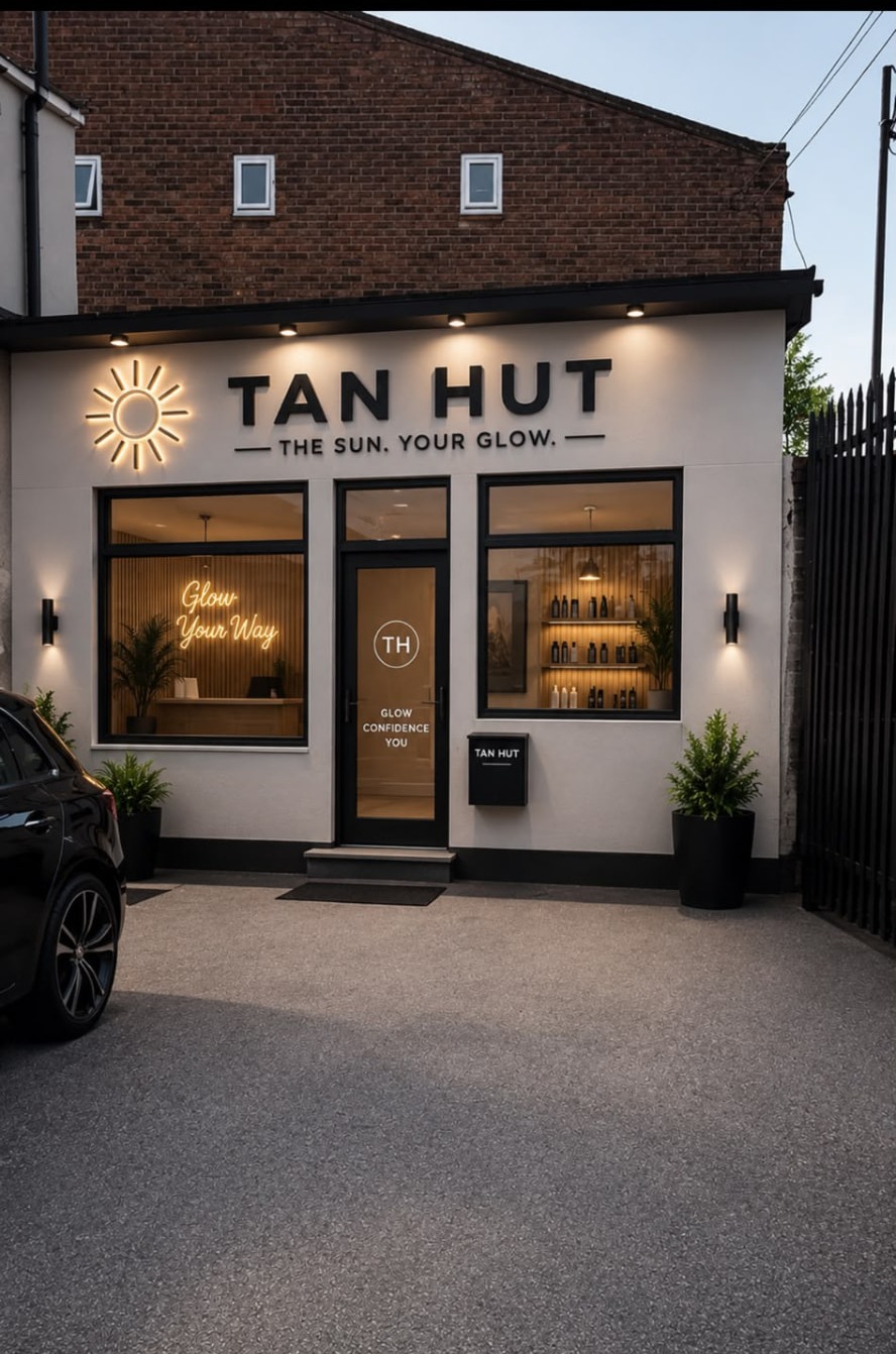 The Tan Hut shopfront in Luton at dusk with warm neon sun sign and glowing windows